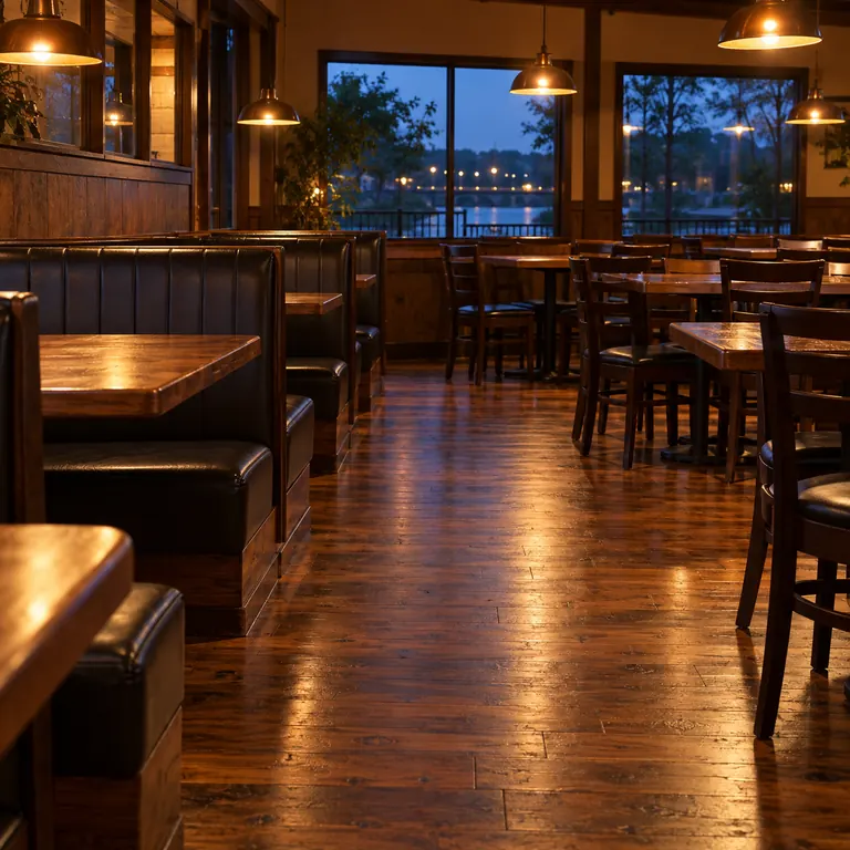 A restaurant dining room with a polished wood floor at dusk